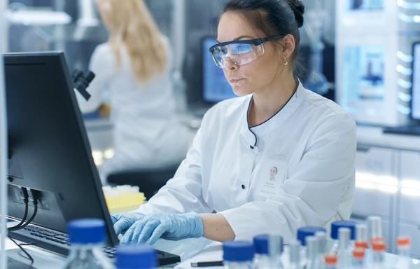 woman-working-in-lab-with-white-coat-and-goggles