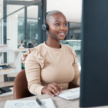 black-professional-woman-in-virtual-meeting on desktop computer in office wearing light brown sweater