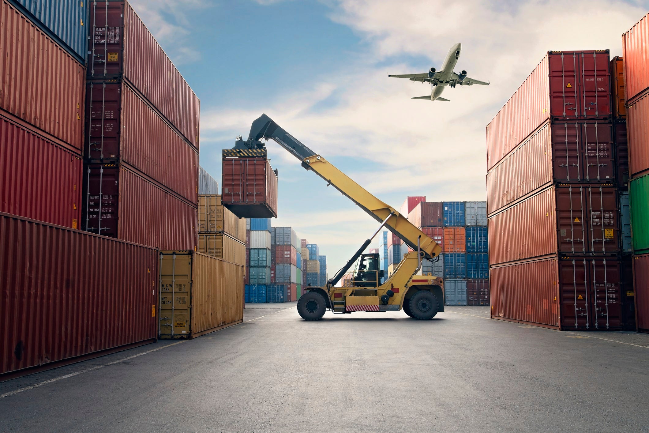 Airplane flying above container port