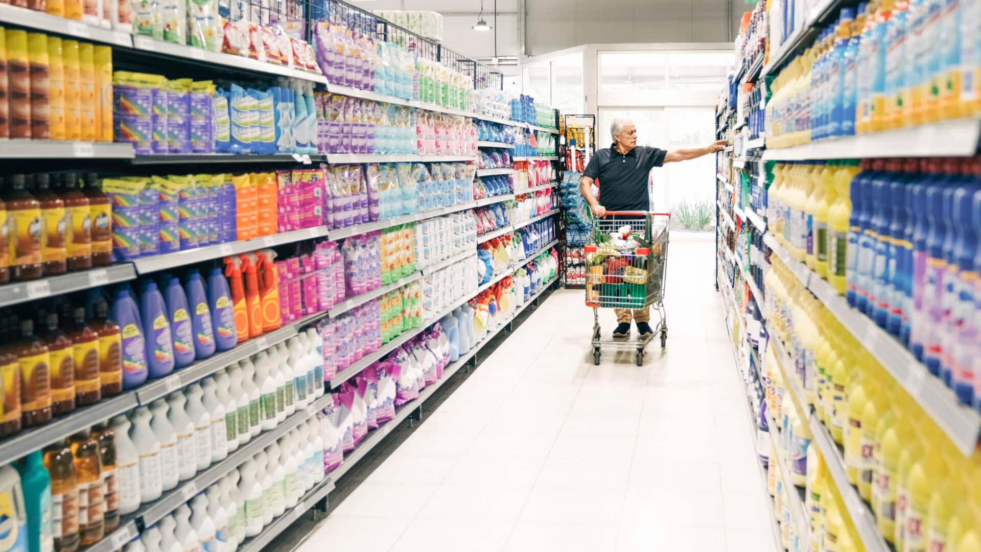 Senior man with shopping cart in supermarket aisle