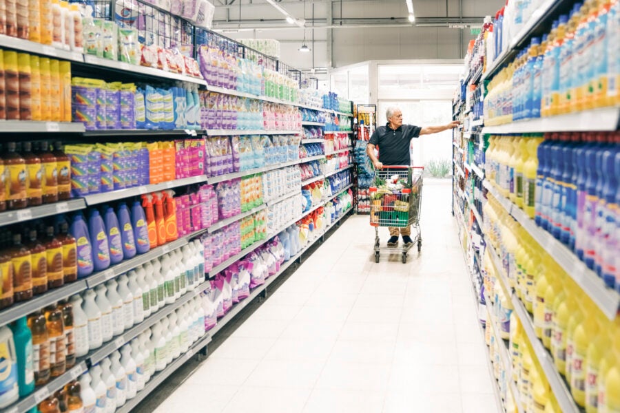 Senior man with shopping cart in supermarket aisle