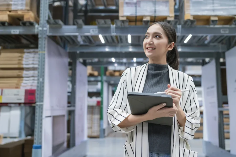 Portrait of asian woman business owner using digital tablet checking amount of stock product inventory on shelf at distribution warehouse factory.logistic business shipping and delivery service