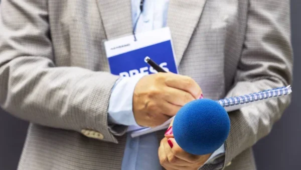 Reporter's hands with a microphone and tablet.
