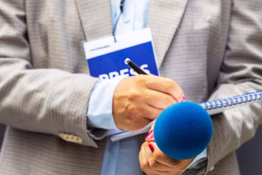 Reporter's hands with a microphone and tablet.