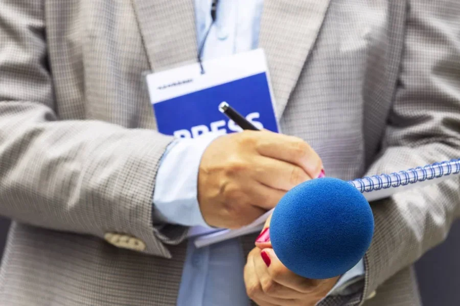 Reporter's hands with a microphone and tablet.