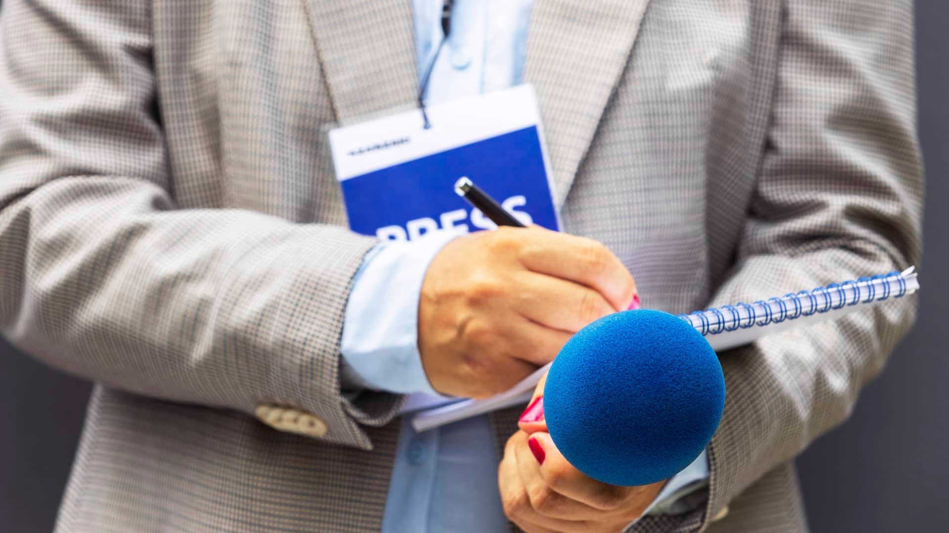 Reporter's hands with a microphone and tablet.