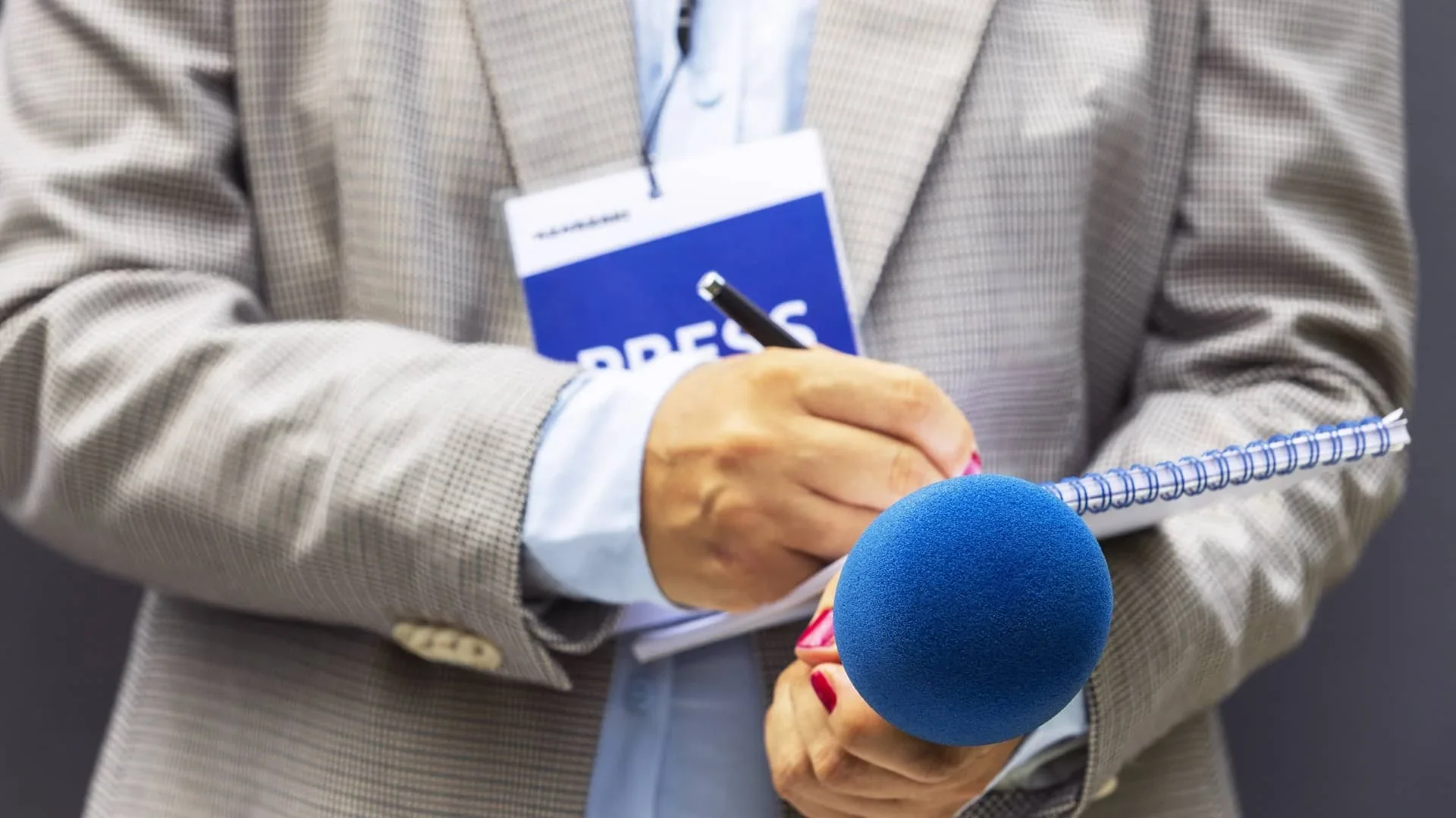 Reporters hands with a microphone and tablet.