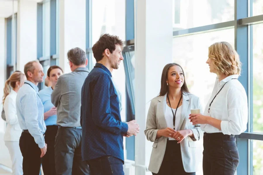 Multiracial group of entrepreneurs discussing during coffee break at business seminar. Group of people standing and talking in the corridor of a business center. Networking concept.