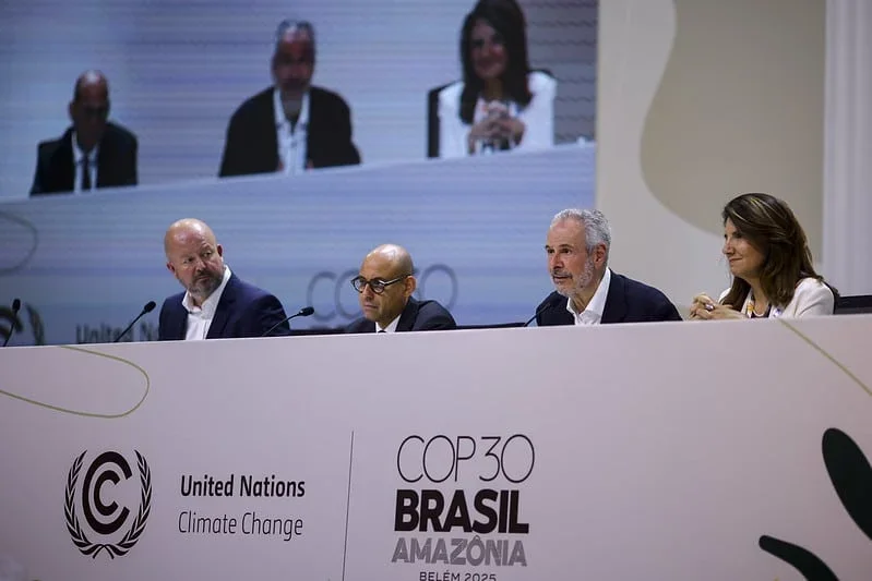 Delegates at COP30 in Belém, Brazil, discussing climate change initiatives amidst the Amazon rainforest backdrop.